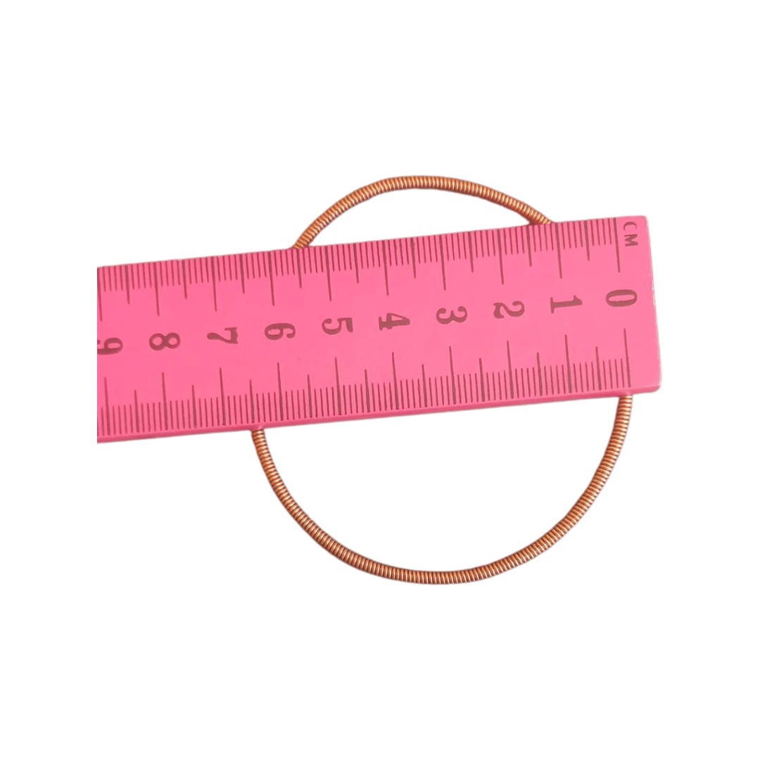 Pink measuring tape with a copper Venda bangles on a white background