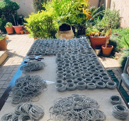 Collection of metal coils on a table outdoors with plants in the background